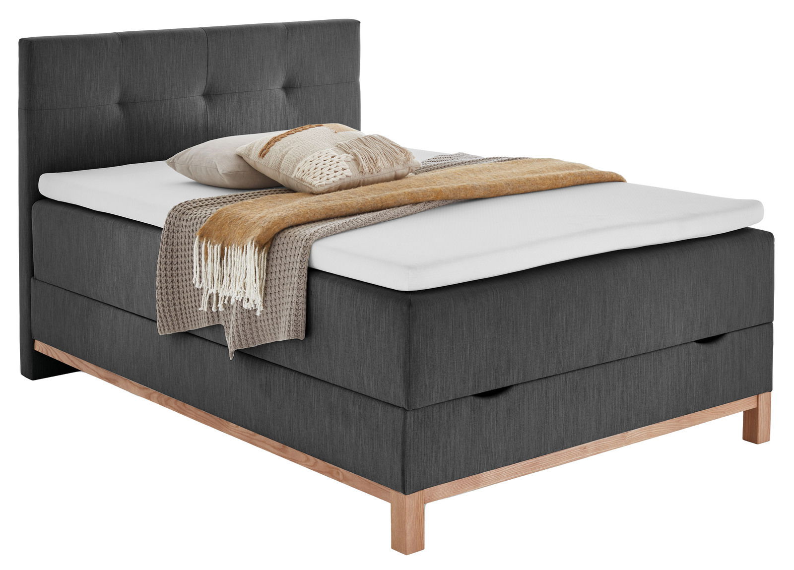 Boxspringbett CATANIA in dunklem Stoff mit Holzfüßen, seitliche Perspektive, dekoriert mit Kissen und Decke.