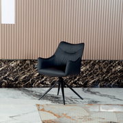 Zwarte fauteuil met een modern ontwerp, op een marmeren vloer voor een geribbelde muur, gezien van voren.