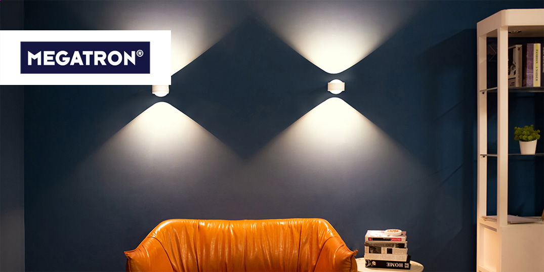 Zwei Wandlampen leuchten ein dunkles Zimmer mit orangefarbenem Sessel und Regal aus.