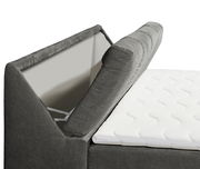 Seitliche Nahaufnahme eines grauen Boxspringbetts mit hochgeklapptem Kopfteil und weißer Matratze.
