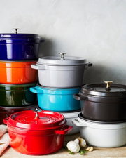 Verschiedene bunte Bräter Cocotte 24cm rund, gestapelt in einer seitlichen Perspektive.