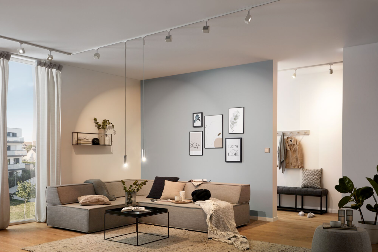 Moderne Wohnzimmerbeleuchtung mit Schiene und Strahlern an der Decke, seitliche Perspektive.