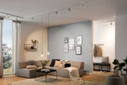 Moderne Wohnzimmerbeleuchtung mit Schiene und Strahlern an der Decke, seitliche Perspektive.