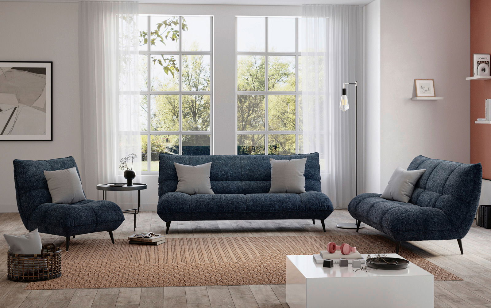 Modernes Wohnzimmer mit einem blauen 2-Sitzer-Sofa und zwei passenden Sesseln, frontal betrachtet, vor großen Fenstern mit Blick ins Grüne.