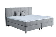 Graues Boxspringbett mit hohem Kopfteil und drei Kissen, seitliche Perspektive