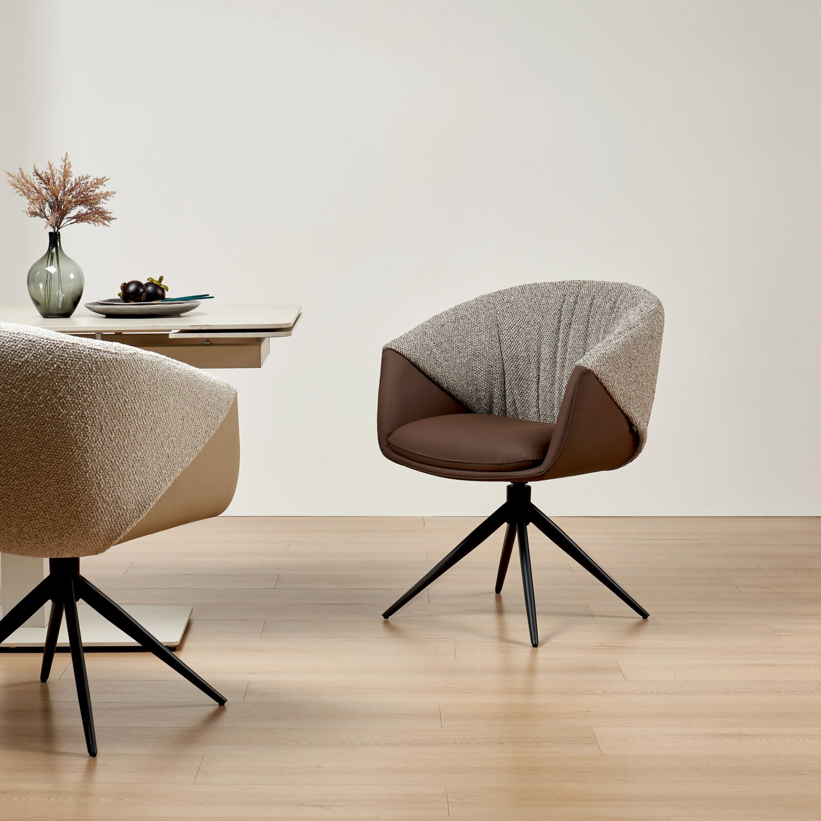 Moderne fauteuil met bruine zitting en rugleuning van stof met patroon, op een zwart draaipootonderstel, gezien vanaf de zijkant in een minimalistische ruimte.