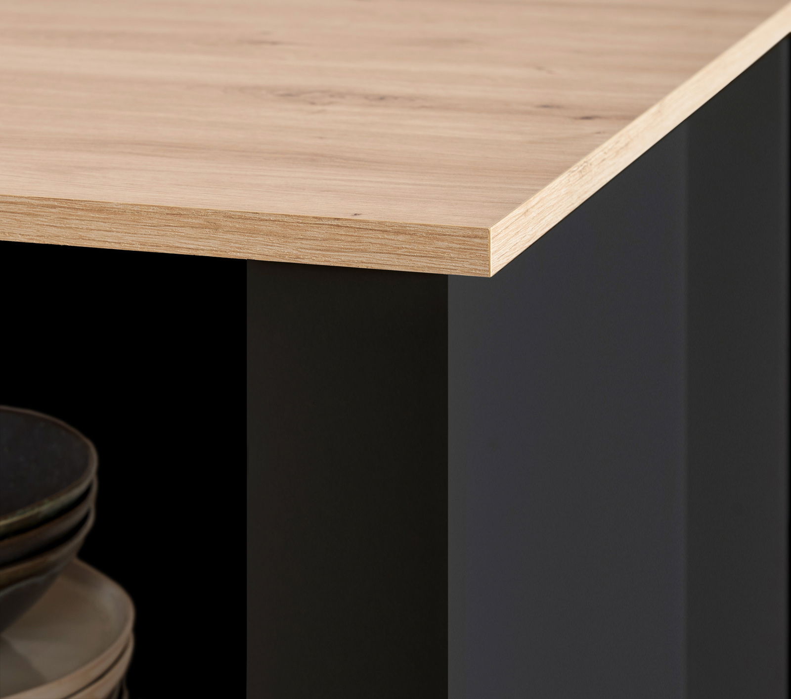 Detailansicht einer Kücheninsel mit Holzarbeitsplatte und schwarzem Korpus, Perspektive von der Ecke.