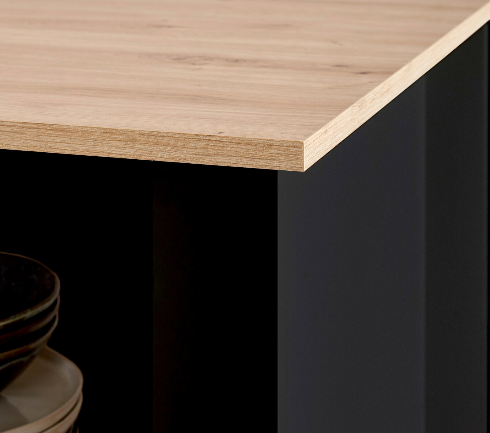 Detailansicht einer Kücheninsel mit Holzarbeitsplatte und schwarzem Korpus, Perspektive von der Ecke.