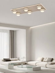 Moderne LED-Deckenleuchte mit sechs runden Leuchtelementen in einem stilvollen Wohnzimmer, Perspektive von unten.