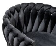 Nahaufnahme eines Sessels mit geflochtenem, schwarzem Samtbezug, seitliche Perspektive