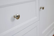 Nahaufnahme eines weißen Sideboards mit silbernen Knöpfen, seitliche Perspektive