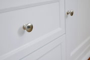 Nahaufnahme eines weißen Sideboards mit silbernen Knöpfen, seitliche Perspektive