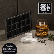Flexible Eiswürfelform aus Silikon, seitliche Perspektive, mit Eiswürfeln und einem Glas Getränk auf einem Tisch.