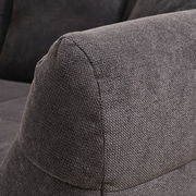 Nahaufnahme eines grauen Big-Sofas mit strukturiertem Stoffbezug, seitliche Perspektive auf die Armlehne.