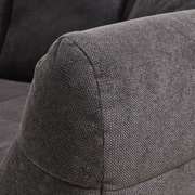 Nahaufnahme eines grauen Big-Sofas mit strukturiertem Stoffbezug, seitliche Perspektive auf die Armlehne.