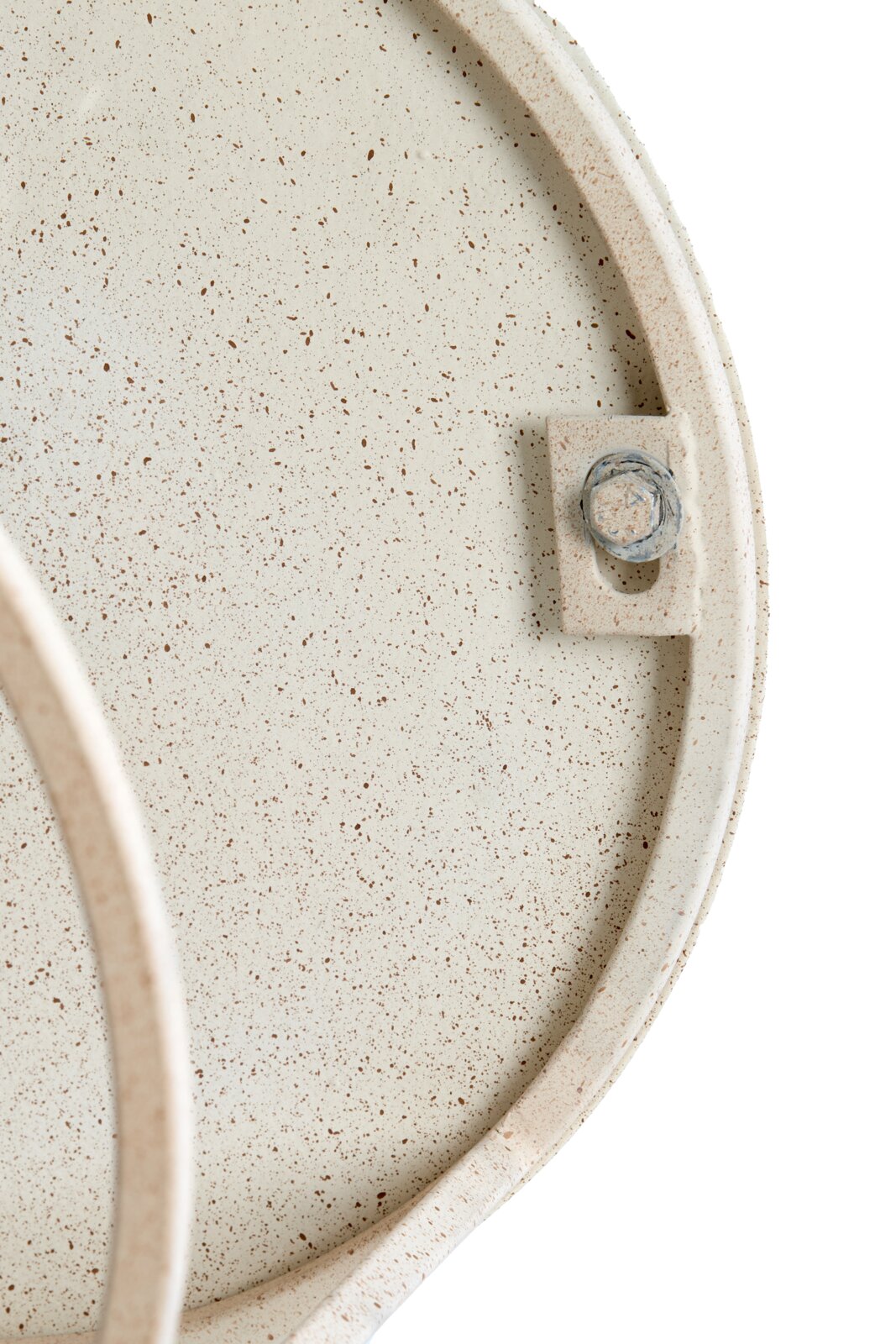 Nahaufnahme eines Couchtischs mit gesprenkelter Oberfläche und sichtbarer Schraube, von oben betrachtet.