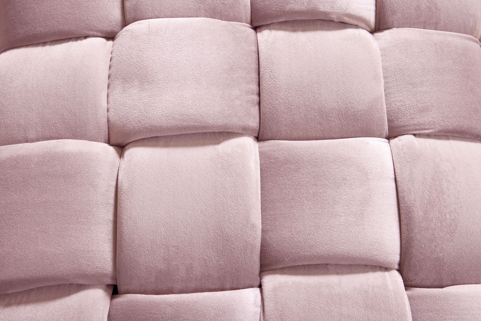 Nahaufnahme eines gepolsterten Hockers mit weichem, rosa Stoff in einem geflochtenen Muster.