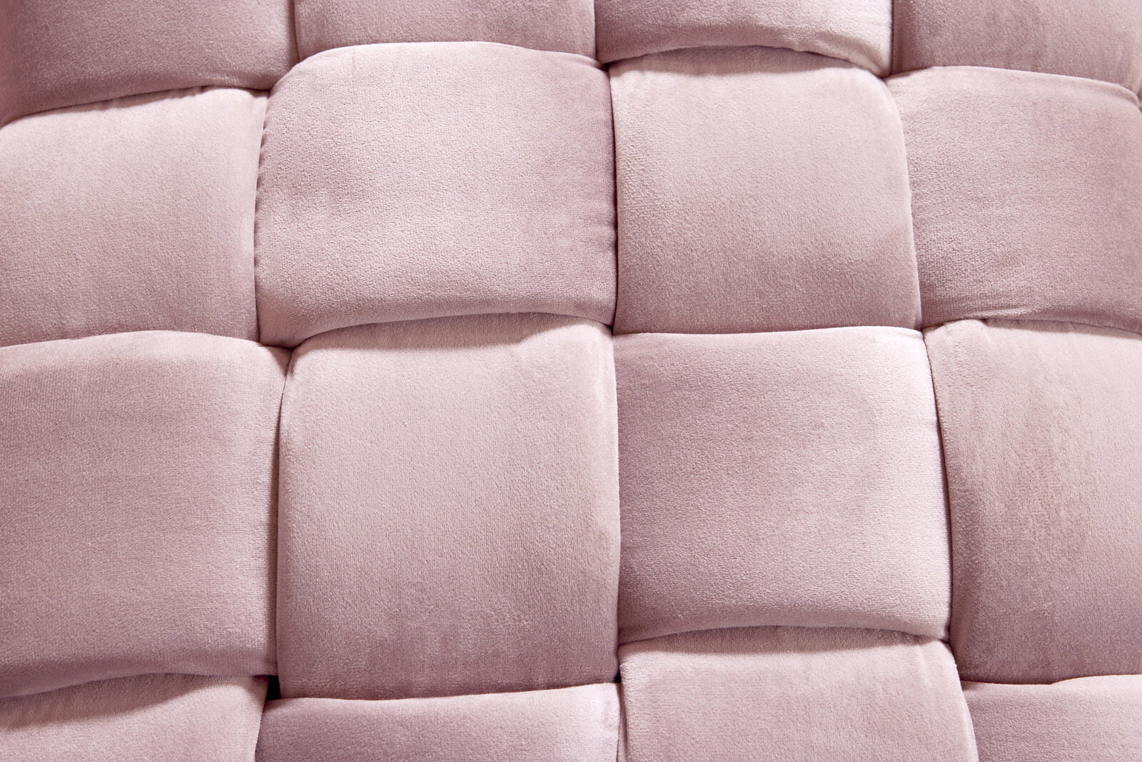 Nahaufnahme eines gepolsterten Hockers mit weichem, rosa Stoff in einem geflochtenen Muster.