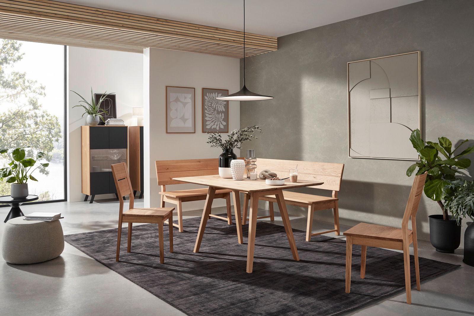 Valnatura Esstisch LARINO Moderne Esszimmer-Einrichtung mit Holztisch, Eckbank und Stühlen in einem hellen Raum mit Pflanzen und Wanddekorationen, seitliche Perspektive.