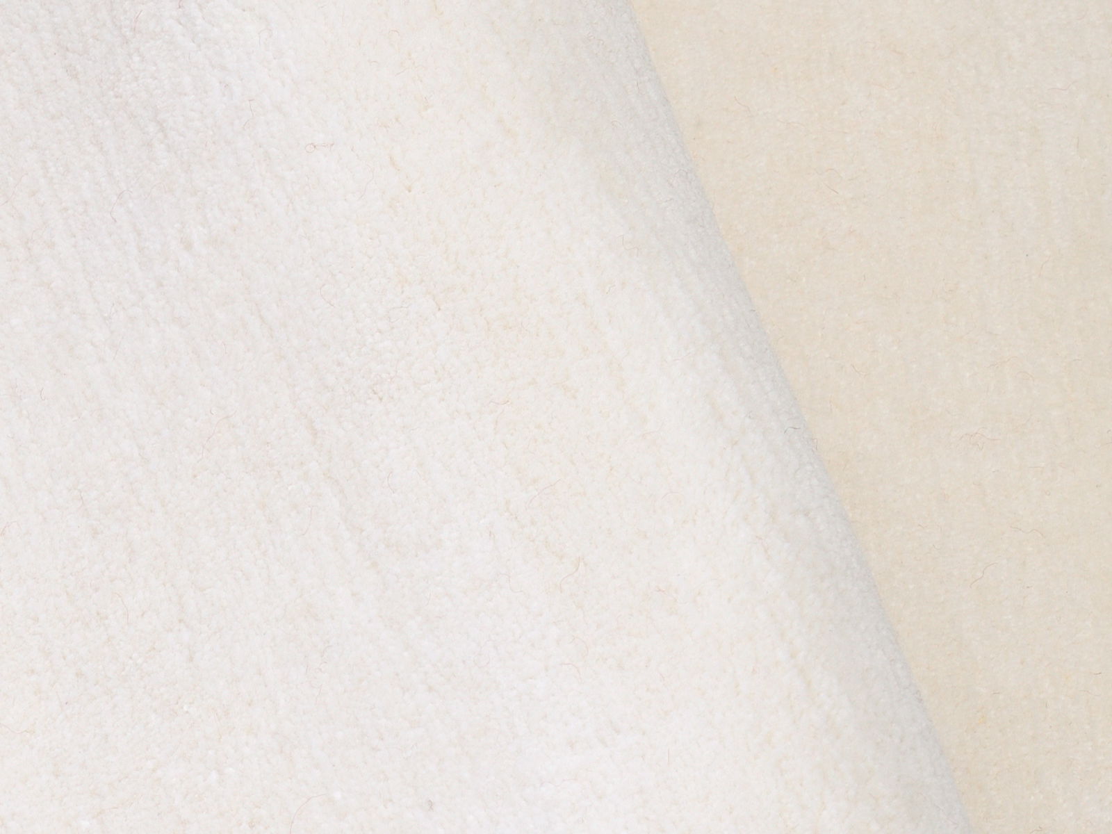 Nahaufnahme eines weißen Wollteppichs mit weicher Textur.