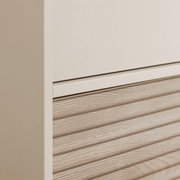 Nahaufnahme eines Kleiderschranks mit einer Kombination aus glatter und holzstrukturierter Oberfläche, seitliche Perspektive.