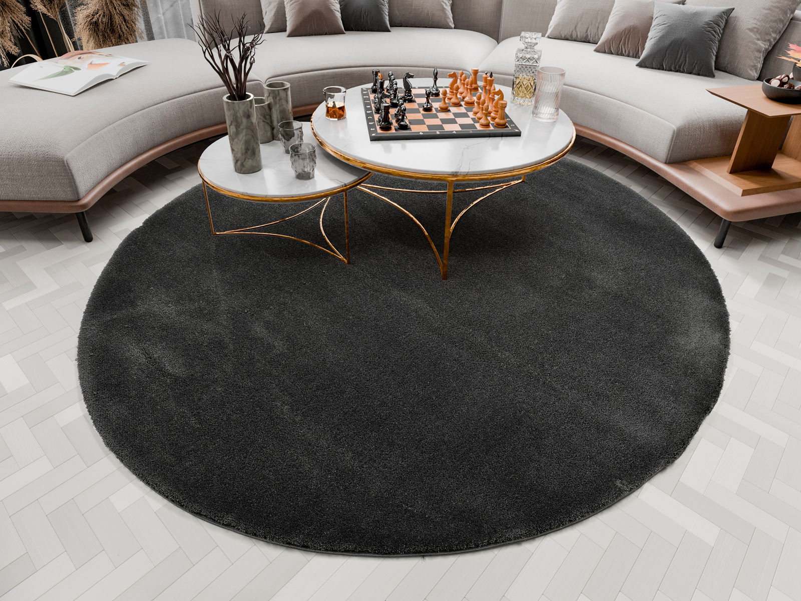 Runder, dunkelgrauer Hochflor-Teppich in einem modernen Wohnzimmer, von oben betrachtet. Der Teppich liegt unter einem runden Couchtisch mit Marmorplatte und goldenen Beinen, umgeben von einem geschwungenen Sofa.