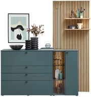 Moderne Sideboardkombination VANYA von Venjakob in stilvollem Design, mit grünen Schubladen und Glastür, dekoriert mit Kunstobjekten und Pflanzen, aus frontaler Perspektive.