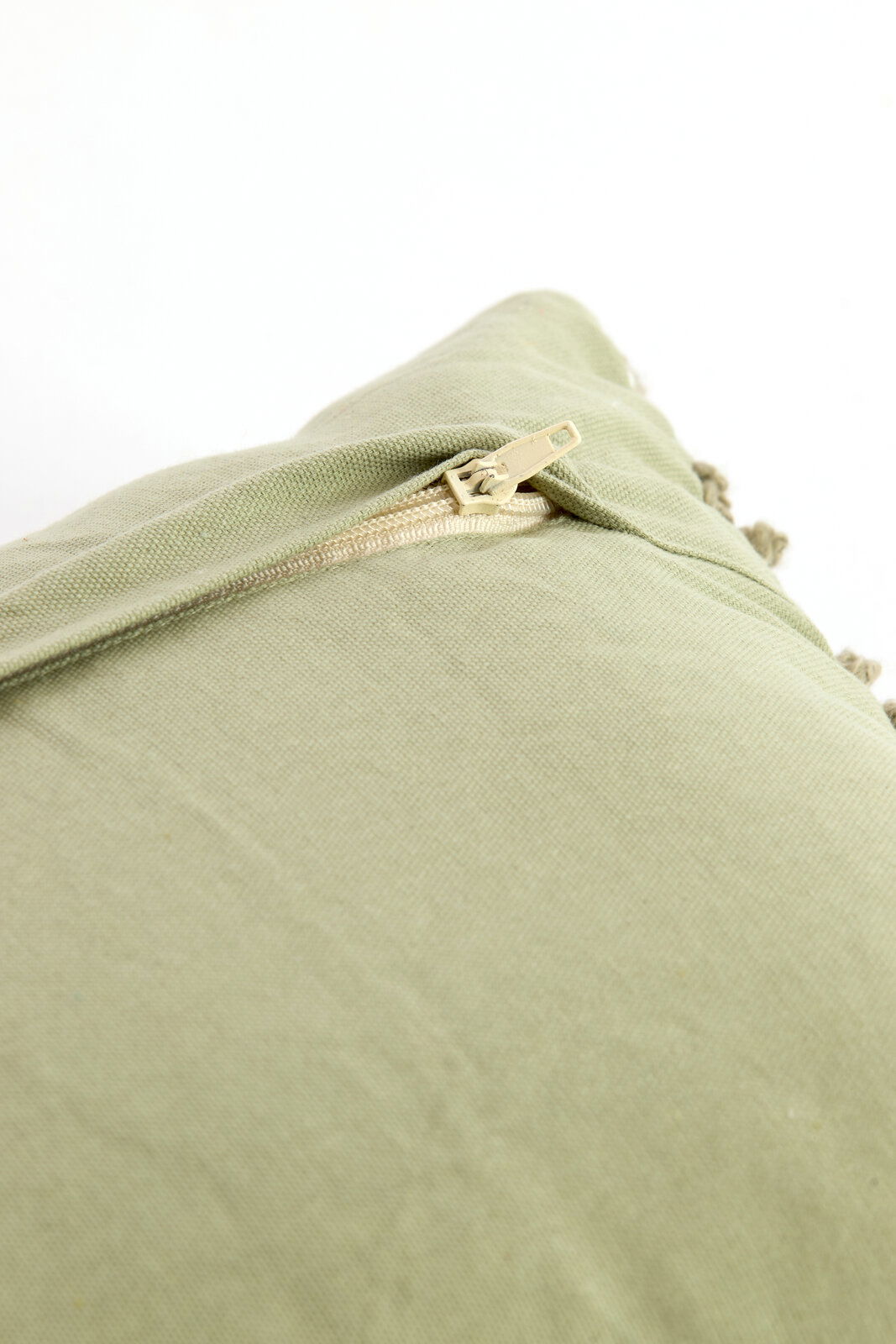 Nahaufnahme eines grünen Kissens mit Reißverschluss, perspektivisch von oben fotografiert.