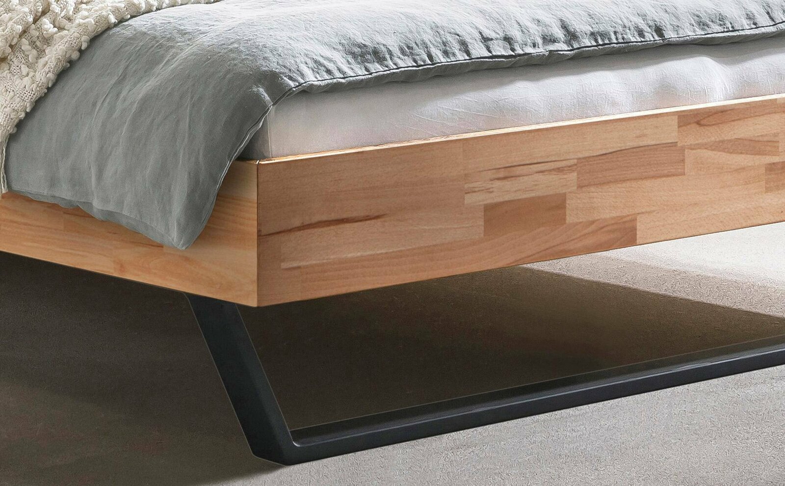 Nahaufnahme eines modernen Bettgestells aus Holz mit Metallbeinen, seitliche Perspektive