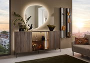 Moderner Wandspiegel mit organischer Form, beleuchtet, über einem stilvollen Sideboard in einem eleganten Wohnzimmer mit Blick auf die Stadt bei Sonnenuntergang.