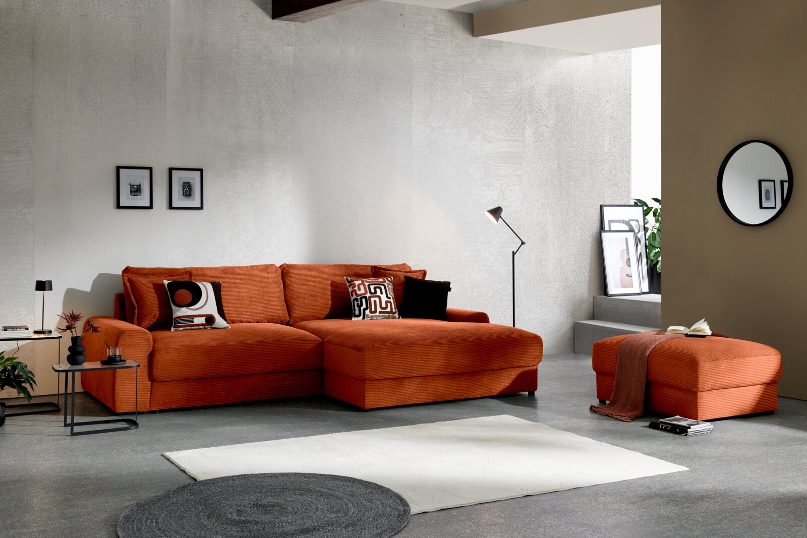 Moderne oranje hoekbank met brede chaise longue en bijpassende poef in een minimalistische woonkamer, vooraanzicht licht van links