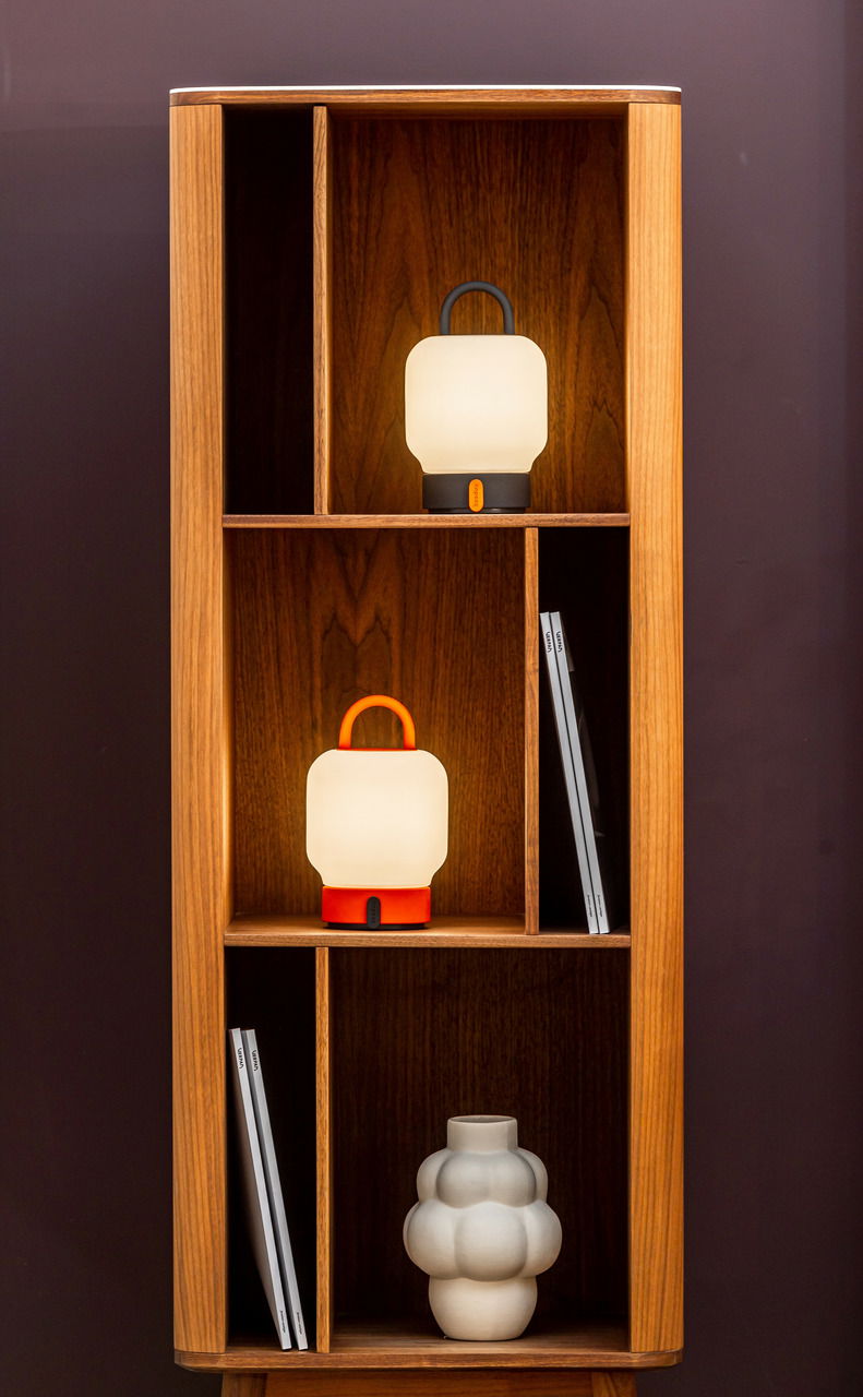 Zwei tragbare Lampen in einem Holzregal, eine in Anthrazit und eine in Rot, mit einem modernen Design. Frontalansicht.