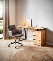 Moderner Schreibtisch aus Holz mit schwarzem Metallgestell, seitlich von einem grauen Bürostuhl und einer kleinen Tischlampe begleitet, in einem hellen Raum mit Holzboden und natürlichem Licht.