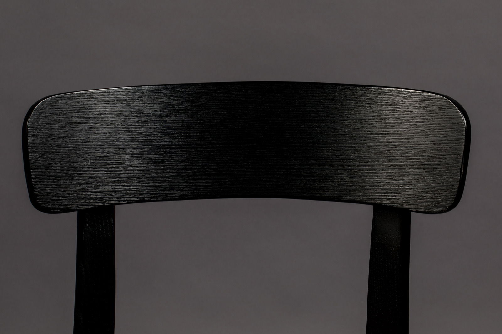 Nahaufnahme der Rückenlehne eines schwarzen Holzstuhls, frontal betrachtet.
