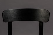 Nahaufnahme der Rückenlehne eines schwarzen Holzstuhls, frontal betrachtet.