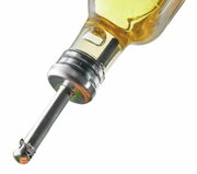 Nahaufnahme eines Ausgießers, der in eine Flasche eingesetzt ist, mit einer metallischen Spitze und einer klaren Flüssigkeit im Hintergrund.