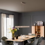 Moderne, längliche LED-Pendelleuchte in Weiß über einem Esstisch in stilvollem Esszimmer, frontale Innenraumansicht aus leicht erhöhter Perspektive