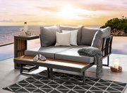 Gartenlounge mit grauen Kissen und Beistelltisch, Blick auf Sonnenuntergang am Meer