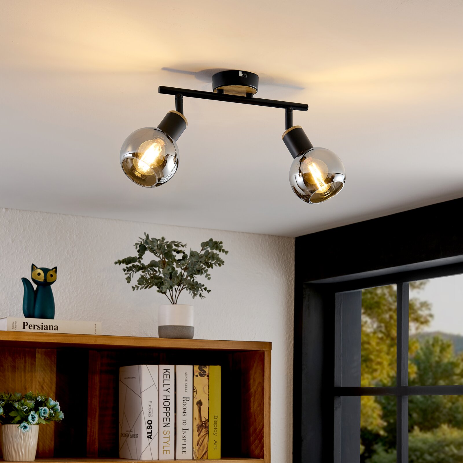 Moderne 2-flammige Deckenleuchte/Spotleiste in Schwarz mit rauchfarbenen Glaskugelschirmen und sichtbaren Filament-Leuchtmitteln, warm leuchtend Perspektive: schräg von unten auf die Decke (Untersicht) im Wohnraum.