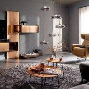 Moderne Pendelleuchten aus Rauchglas in einem Wohnzimmer über Couchtischen, Frontansicht aus leicht schräger Perspektive