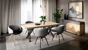 Modernes Esszimmer-Set mit hellem Holztisch und grauen Polsterstühlen auf Teppich, seitliche Perspektive im Raum mit Vorhängen, Pflanzen und Sideboard im Hintergrund.