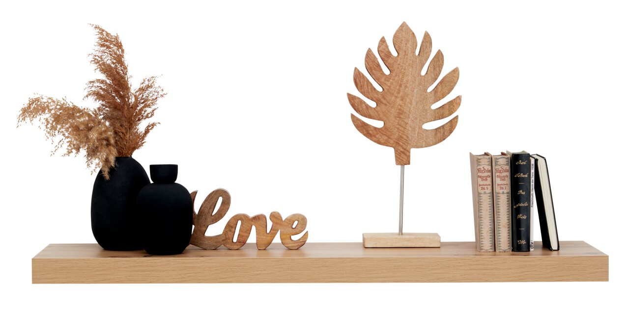 Wandboard aus Holz mit Dekorationen, darunter schwarze Vasen mit Trockenblumen, ein Holzschriftzug 'Love', ein Holzblatt auf Ständer und Bücher. Frontalansicht.