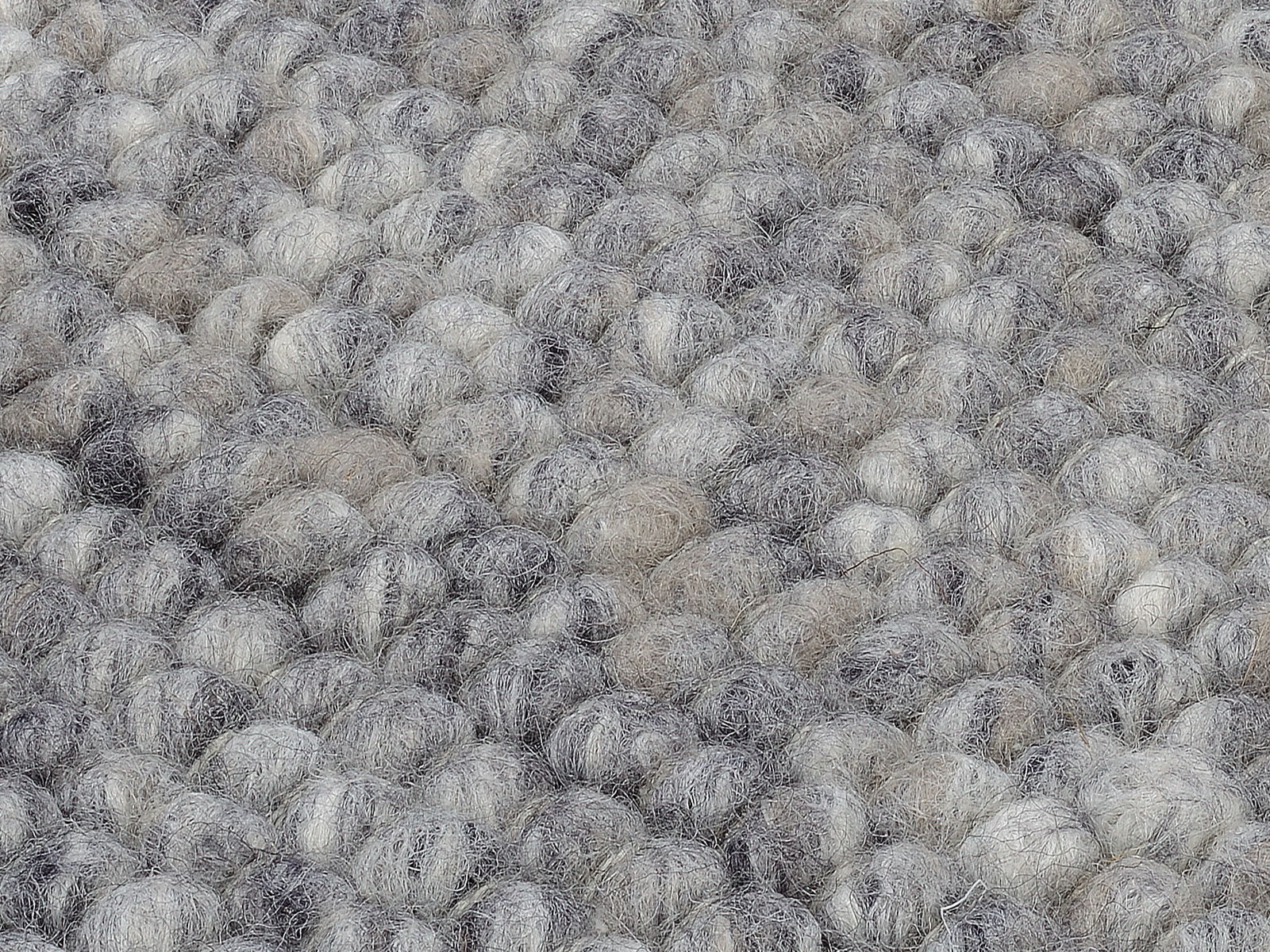 Nahaufnahme eines handgewebten Teppichs mit einer texturierten, grauen und beigen Oberfläche.