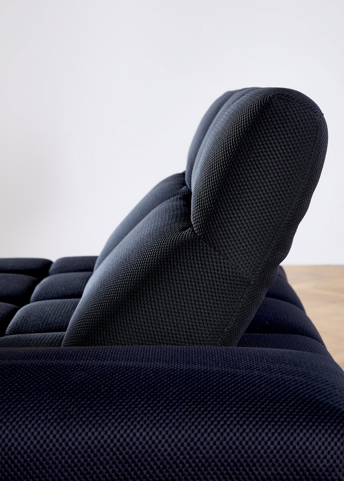 Seitenansicht einer modernen, dunkel gepolsterten Eckgarnitur mit strukturierter Oberfläche.
