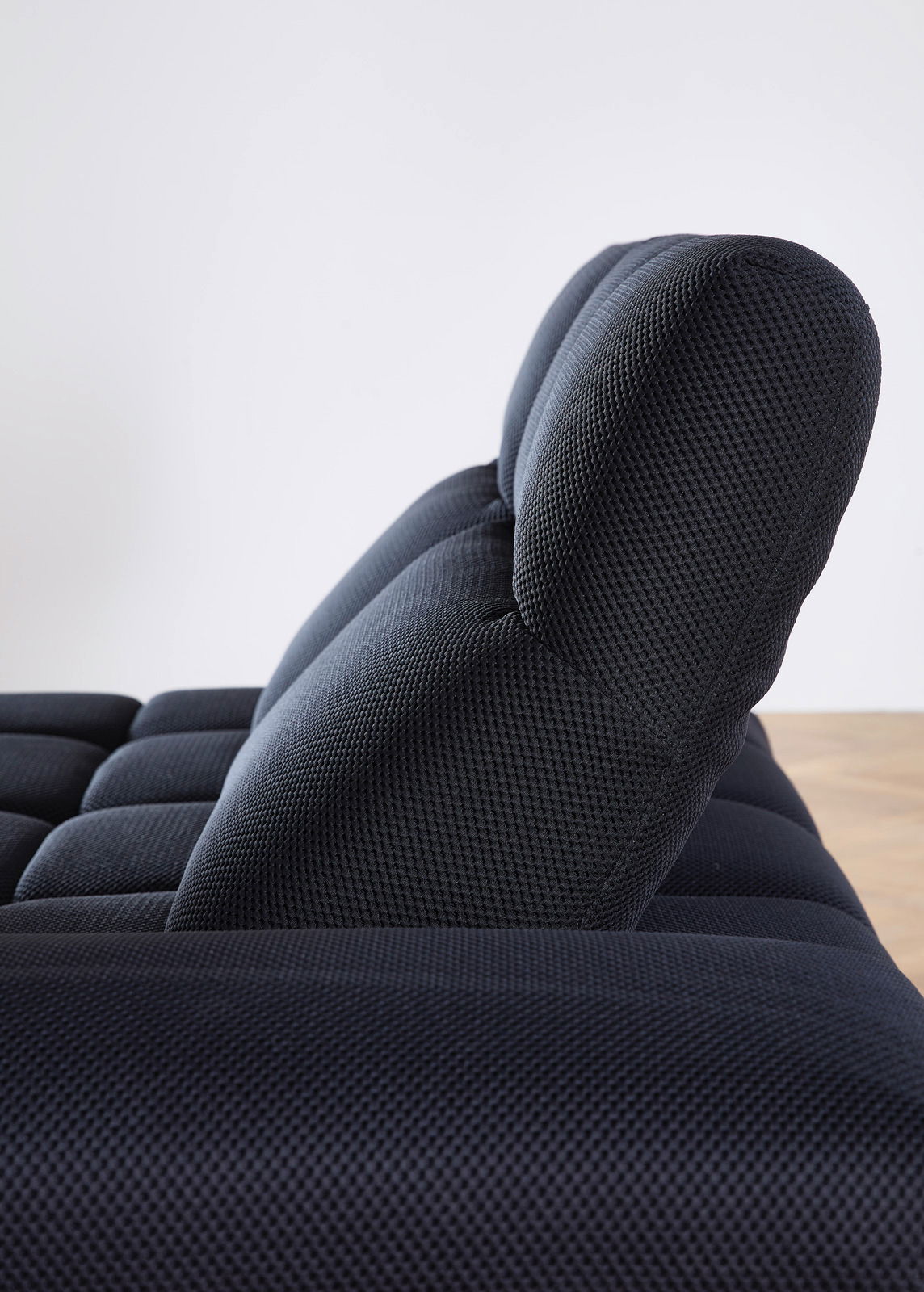 Seitenansicht einer modernen, dunkel gepolsterten Eckgarnitur mit strukturierter Oberfläche.