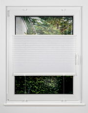Weiße Plissee-Jalousie an einem Fenster, halb heruntergelassen, mit Blick auf einen Garten. Frontalansicht.