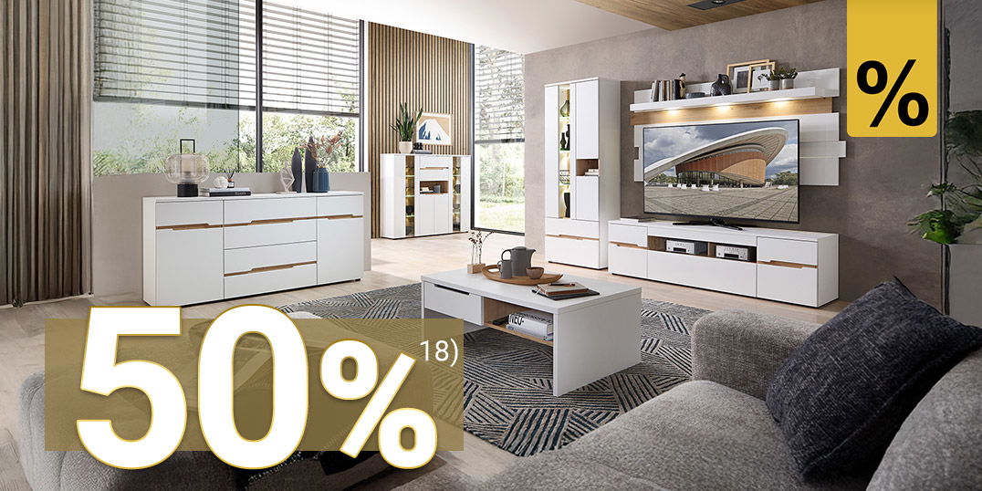 Modernes Wohnzimmer mit weißem Möbelset, großer grauer Couch, Holzdecke, TV-Wand und viel Tageslicht durch große Fenster.