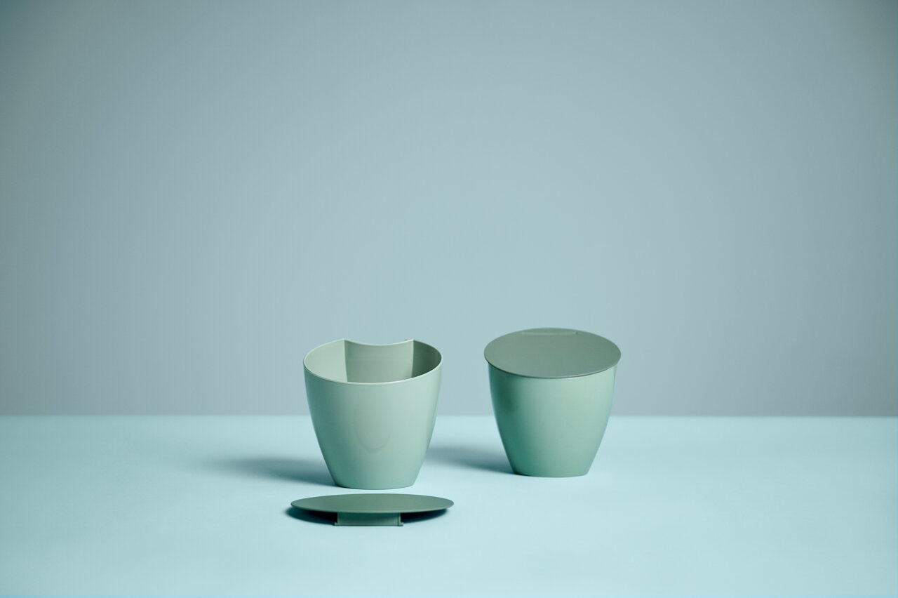 Grüner Bio-Abfallbehälter in drei Teilen, frontal fotografiert.