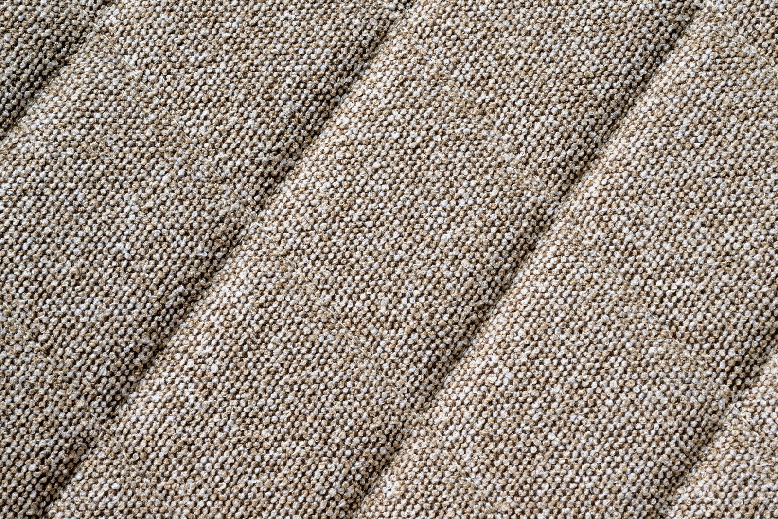 Nahaufnahme eines beige strukturierten Stoffes in diagonaler Perspektive.