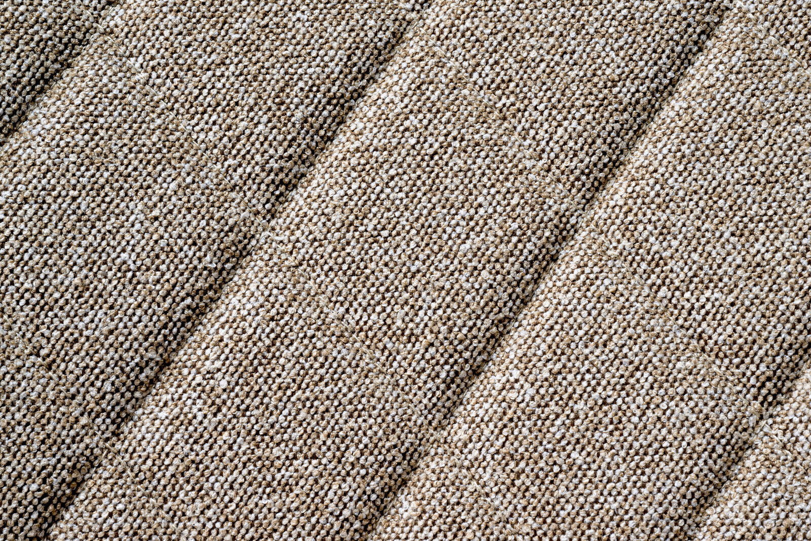 Nahaufnahme eines beige strukturierten Stoffes in diagonaler Perspektive.